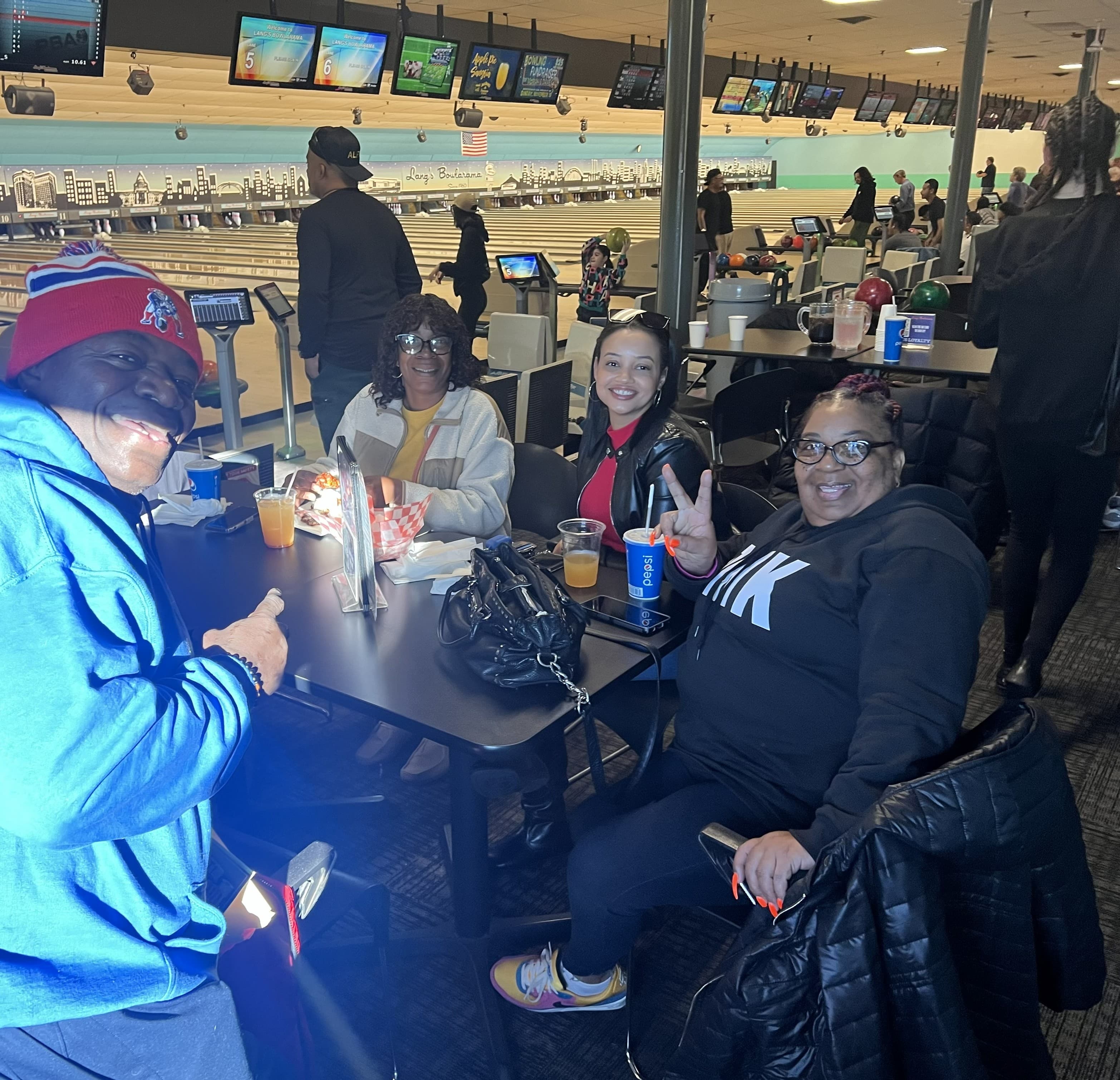 Community members seated on benches together at a Lead By Example bowling event