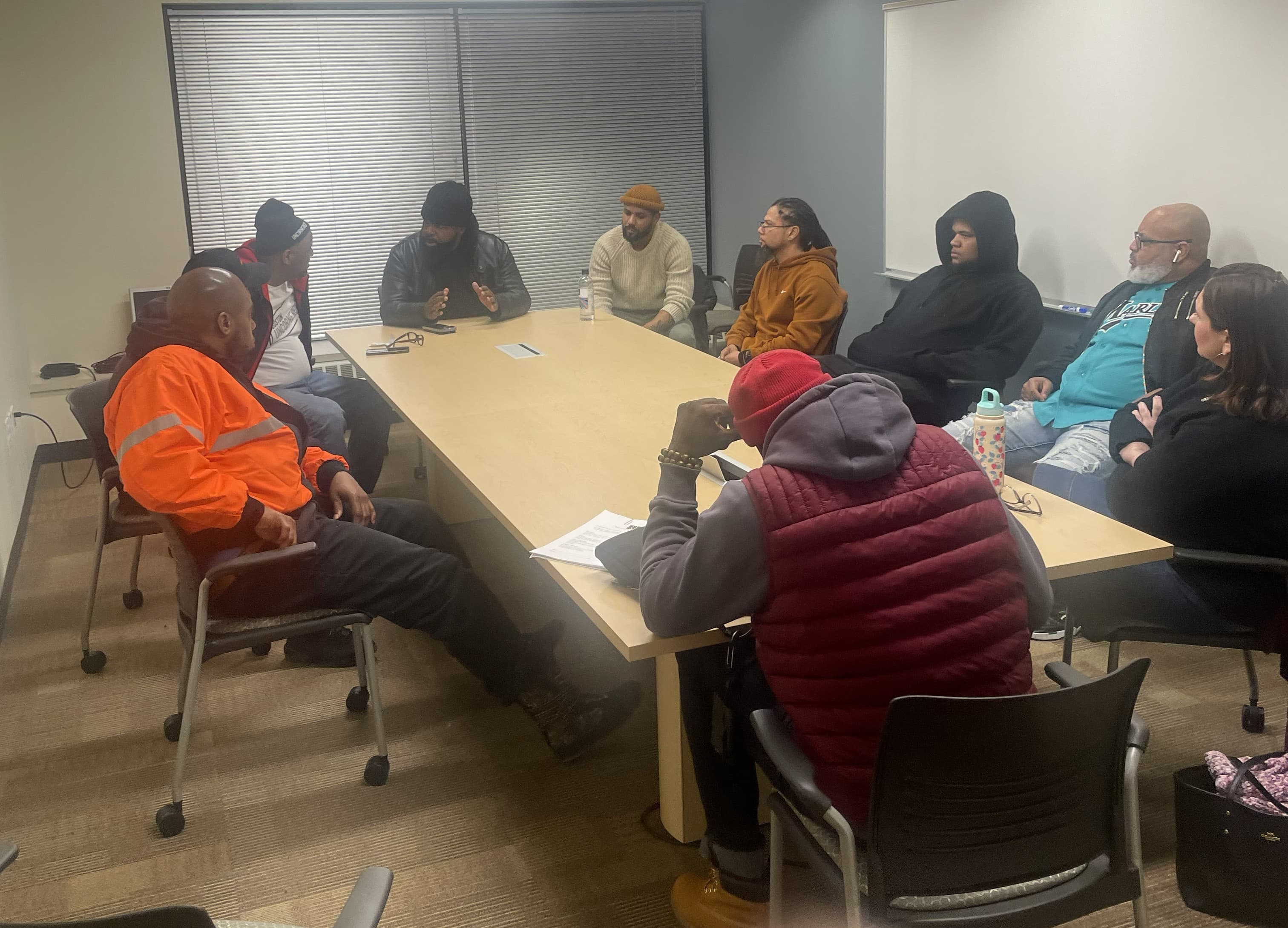 Community members and advocates seated around a conference table during a Lead By Example planning session